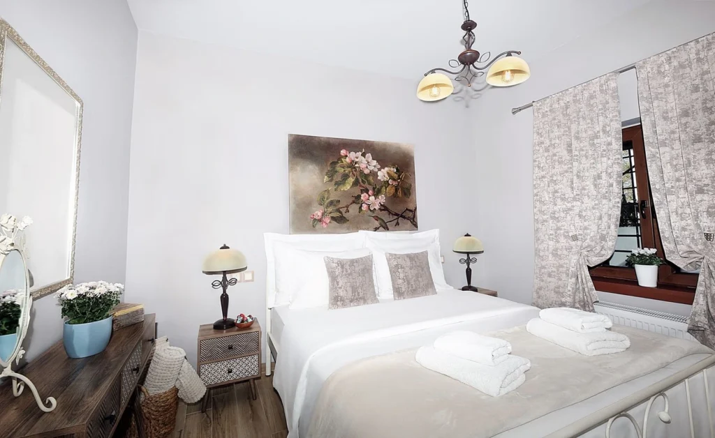 Ρομαντικό υπνοδωμάτιο με διπλό κρεβάτι, λευκά σεντόνια και πίνακα με άνθη στην Πορταριά Πηλίου"