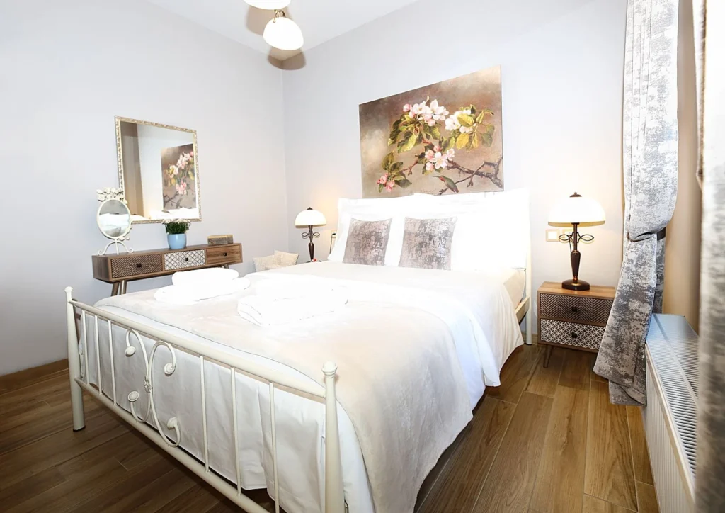 Άνετο υπνοδωμάτιο με διπλό κρεβάτι, ξύλινο πάτωμα, κομοδίνα και διακόσμηση με λουλούδια