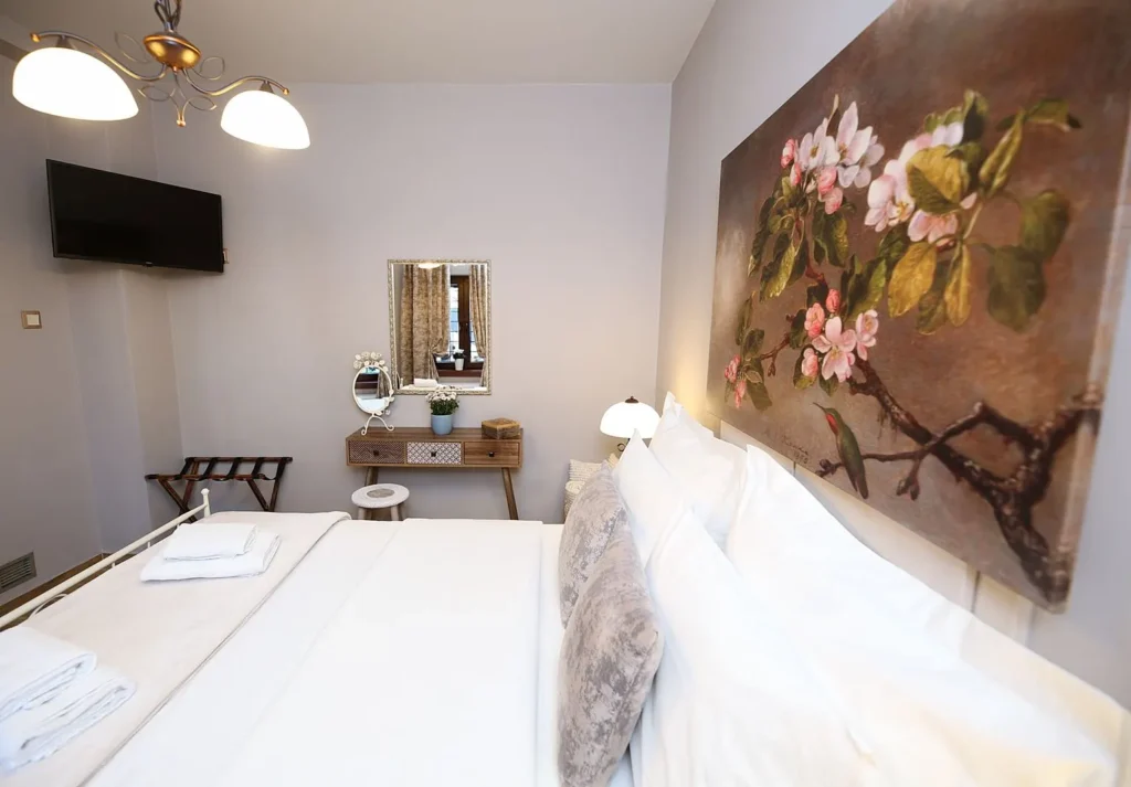 Κομψό υπνοδωμάτιο με διπλό κρεβάτι, έργο τέχνης με άνθη, τηλεόραση τοίχου και τουαλέτα