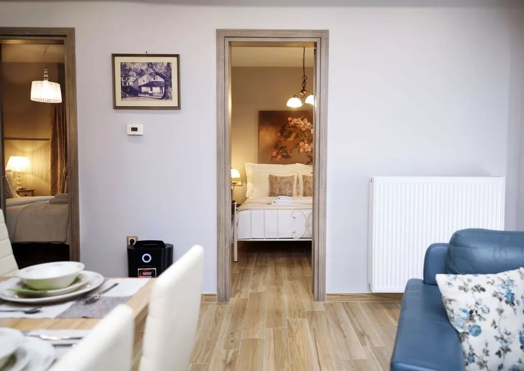 Θέα από το σαλόνι προς δύο υπνοδωμάτια με κομψή διακόσμηση και φωτισμό.