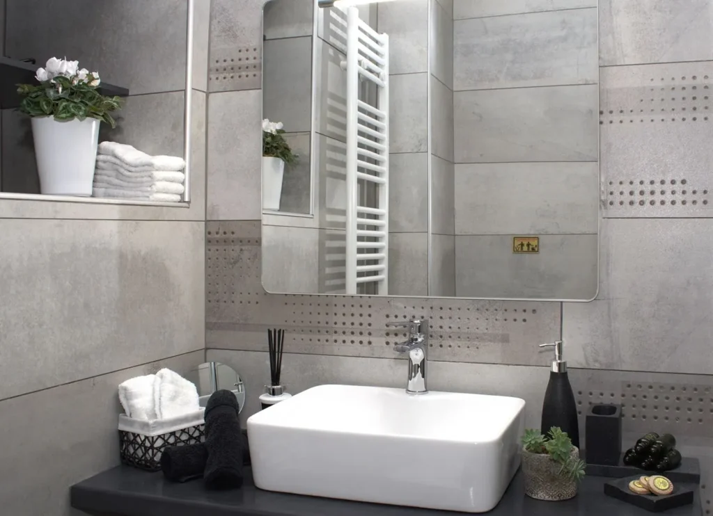 Νιπτήρας μπάνιου με καθρέφτη, μαύρες πετσέτες, φυτά και είδη περιποίησης στο Venus Guesthouse Πηλίου